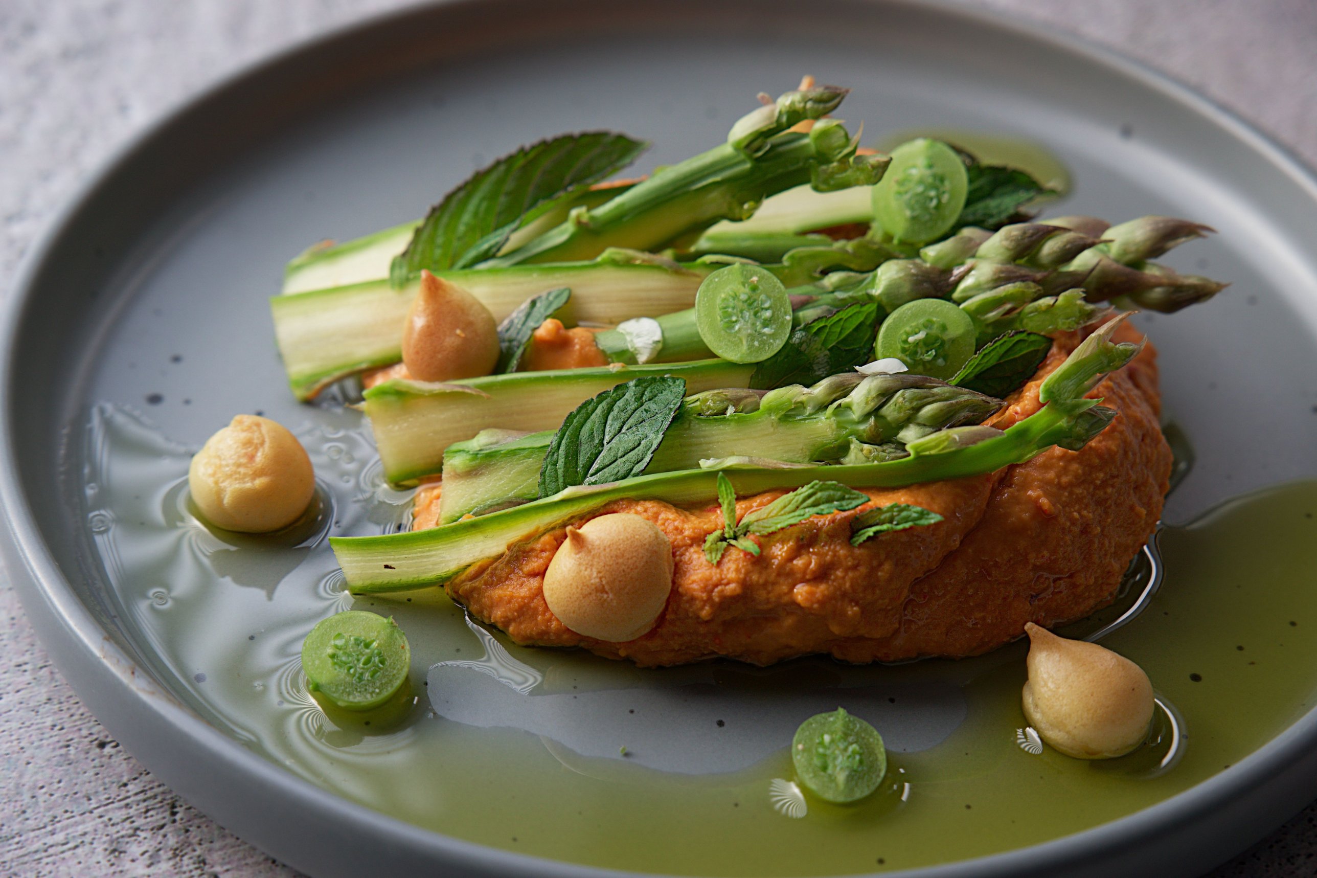 Grüner Spargel auf orangefarbenem Püree